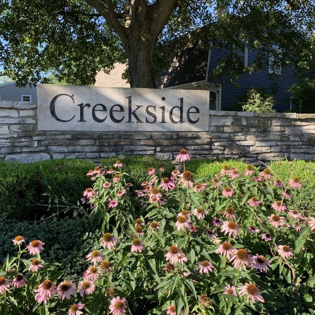 A wall with a plaque that reads “Creekside”